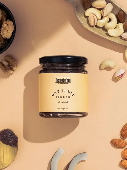 A flatlay composition showcasing the natural ingredients of the Dry Fruit Spread. Arranging the nuts and dried fruits around the jar provides a clear, informative, and visually appealing look at what's inside.