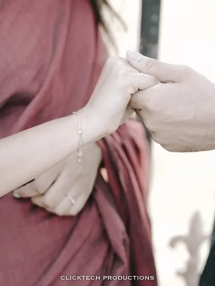 A close-up detail shot of a couple holding hands, showcasing their rings and the texture of their traditional outfits.