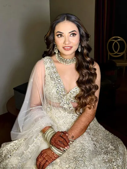 A Sangeet bride in a beautiful white and silver lehenga. The makeup is soft and shimmery, with a focus on glowing skin.