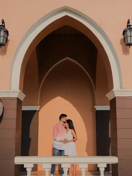 A beautifully composed shot using architectural arches to frame the couple. The warm light and the tender forehead kiss create a deeply romantic and artistic pre-wedding portrait.