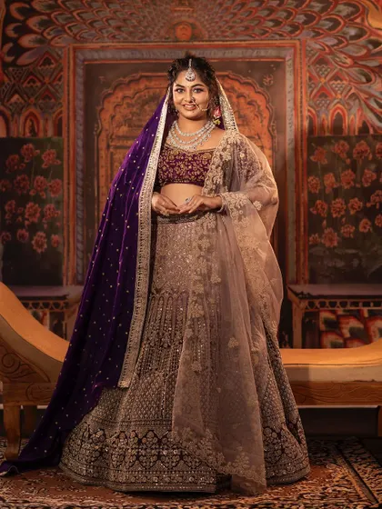This grand lehenga in shades of purple and mauve is perfect for a reception or sangeet. The velvet blouse is heavily embroidered, and the double dupatta, one in sheer net and another in rich velvet, adds a layer of elegance.