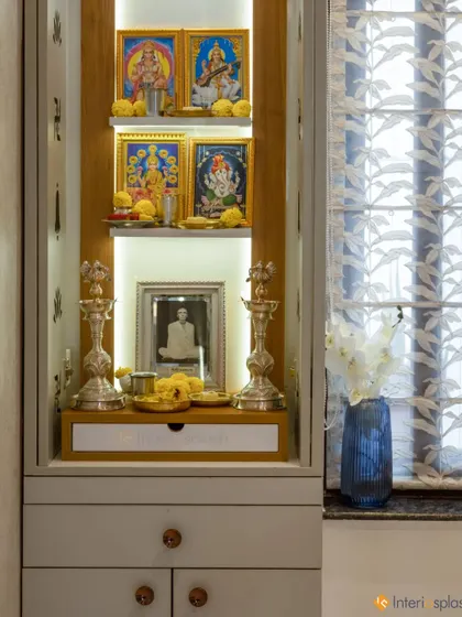 The puja unit with its doors open, revealing the beautifully lit interior with space for deities and photos. The design includes a small drawer for storing puja essentials.