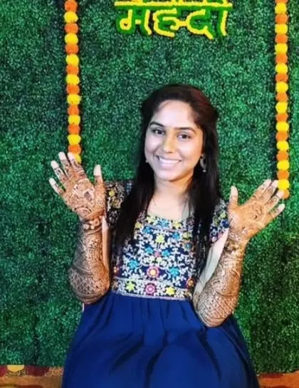 A smiling bride showing off her completed mehandi against a festive backdrop. I love capturing these happy moments.