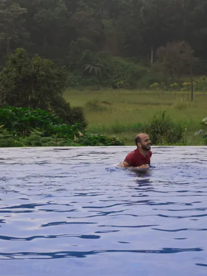 A team member enjoys a refreshing dip in an infinity pool with a stunning view of the forested hills. It's the perfect way to unwind after a day of meetings or adventure.