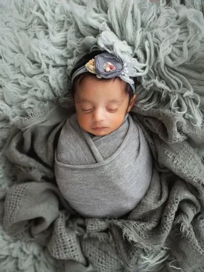 A beautiful solo portrait of one of the twin girls, wrapped in grey with a delicate floral headband. It's important for each twin to have their own moment in the spotlight.