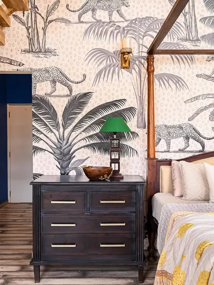 The master bedroom in "Far From The Stone Street," showing the four-poster bed, jungle-themed wallpaper, and a peek into the cobalt blue walk-in wardrobe alley.
