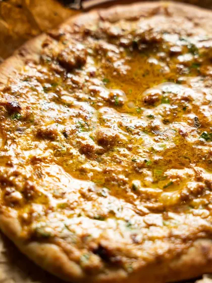 An extreme close-up of a glistening, freshly baked naan bread. This macro shot highlights texture and makes a simple item look incredible.