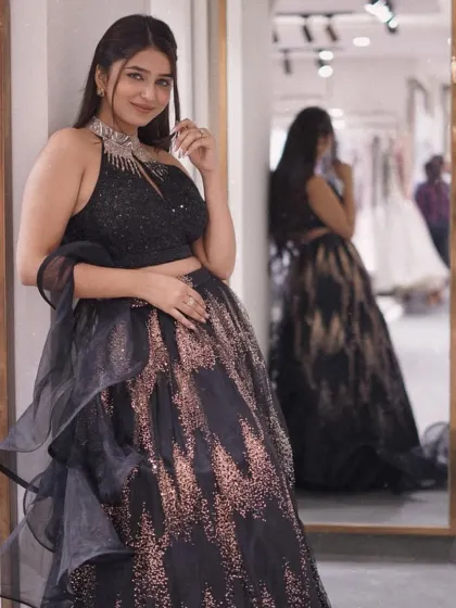 Make a dramatic entrance in this stunning black lehenga. The ruffled dupatta and shimmering gold accents create a look that is both sophisticated and glamorous.