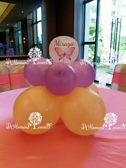 A simple and sweet table centerpiece with a personalized butterfly-themed disc, using the party's color scheme of pastel yellow and purple.