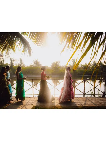 The bride's procession with her bridesmaids, silhouetted against the golden light over the water.