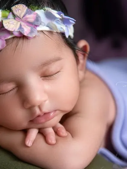 Love at first sight. This close-up of a baby girl in a froggy pose, with a beautiful floral headband, is a perfect example of timeless newborn portraiture.