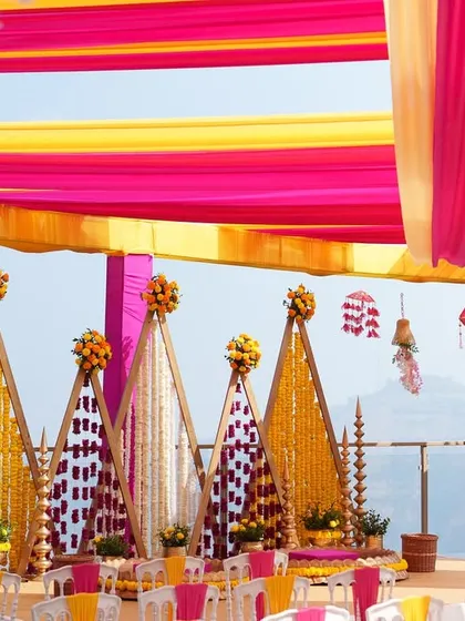 We bring vibrancy to tradition with setups like this stunning outdoor Haldi ceremony. The brilliant pink and yellow drapes create a joyful canopy, while the intricate marigold backdrops and floral arrangements set the stage for a day filled with laughter and blessings.