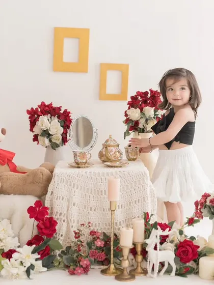 A lovely tea party with a teddy bear friend. This classic and elegant setup, with its red and white floral theme, is perfect for a timeless and sweet photoshoot.