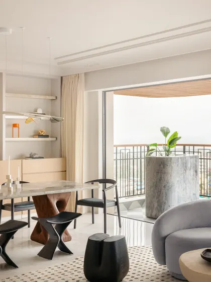 The dining table is a striking centerpiece, with a glass base on one side and a sculptural wooden base on the other, a perfect harmony of clarity and warmth.