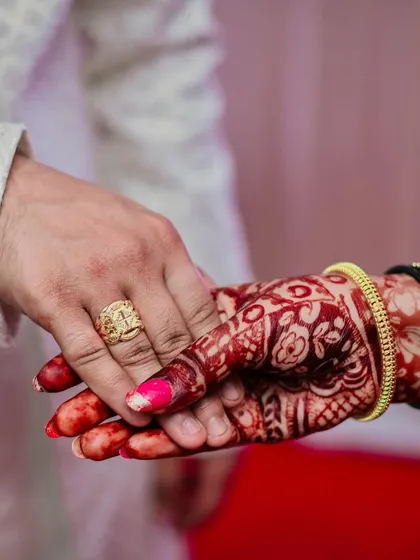 A close-up shot focusing on the couple's hands after the ring ceremony, highlighting the intricate henna and the newly exchanged rings.