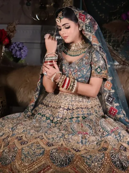 A regal bridal portrait. This image captures the grandeur of the full bridal look, from the elaborate lehenga to the perfectly applied makeup, set against a floral backdrop.