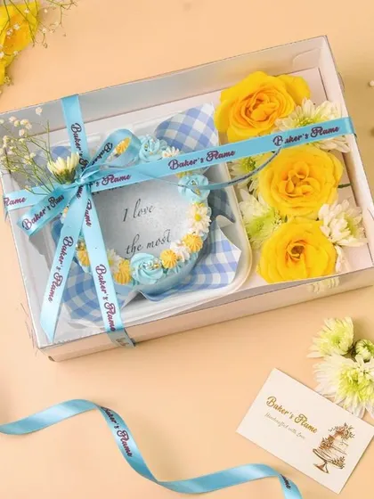 A wider shot of the blue and yellow bakery hamper, showing the branded ribbon and card. This gives a complete picture of the gift package.