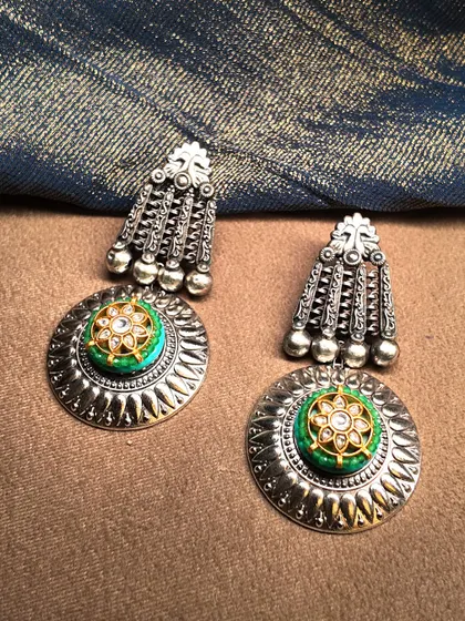 Classics never fade. These silver jhumkas feature a large, circular stud with a green and polki center, perfect for a timeless look.