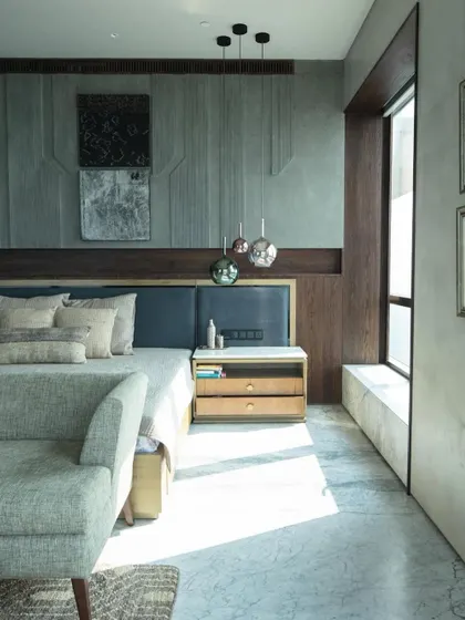 The master bedroom, bathed in sunlight, as seen in Elle Decor. The design is kept refreshingly simple and functional, with an etched stone headboard and curated art providing moments of texture and interest.
