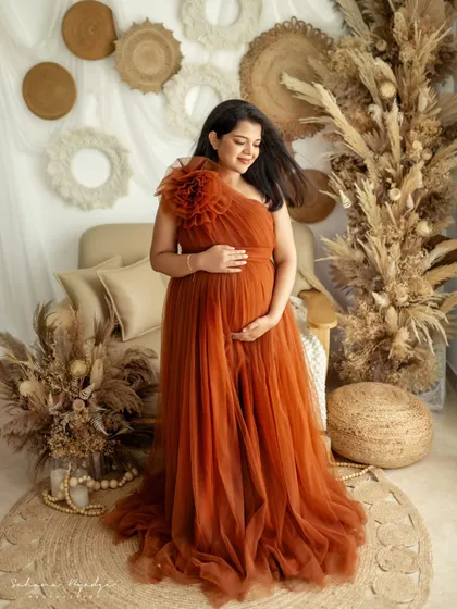 A solo portrait is a powerful way to celebrate your strength and beauty during pregnancy. This mom-to-be is glowing in a gorgeous rust-colored gown, set against a rustic, earthy backdrop that feels both warm and stylish.