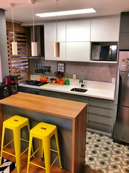 A compact kitchen with a wooden breakfast bar and bright yellow stools. This design proves that even small spaces can be stylish and social.