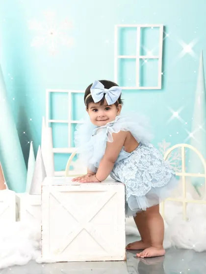 Taking a stand in her winter wonderland. Capturing these "pulling up" moments is a key part of a first birthday milestone session.
