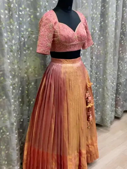 The complete peach lehenga set on display. Notice the delicate tassels and the rich, dual-tone effect of the pleated silk skirt.