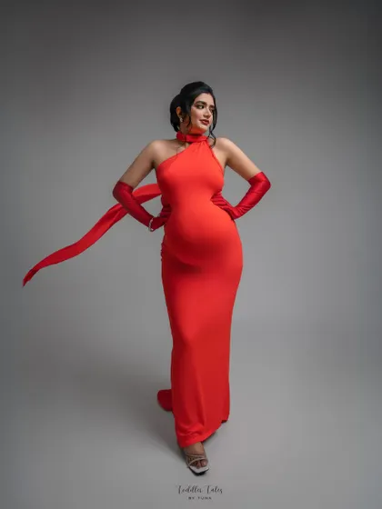 Modern muse in red. This halter-neck gown with matching gloves and a flowing ribbon creates a chic, contemporary silhouette. It’s a perfect example of how maternity style can be both sophisticated and powerful.
