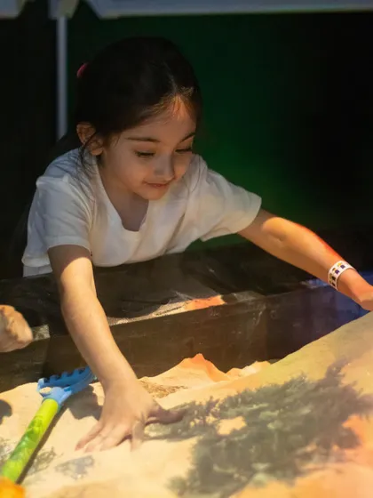 A close-up of a child shaping the illusion sand, watching as the colors and topography change in real-time.