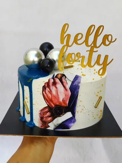 "Hello Forty" indeed. This stylish cake for a man's 40th birthday includes a painted suit detail, a blue drip, and silver and black sphere decorations.
