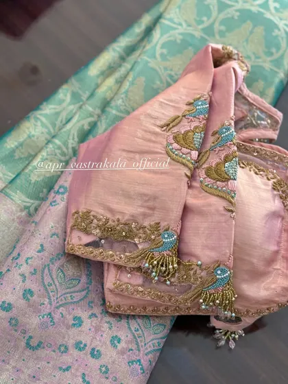 A pink blouse with embroidered bird motifs on the sleeves and a simple back.