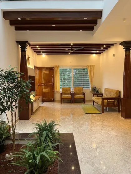 In Mr. Vinay's residence, we used traditional wooden pillars and a beamed ceiling to define the living space within a modern open floor plan. The central courtyard planter brings a touch of nature indoors.
