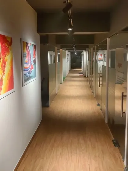 This corridor in a co-working space in Noida is designed to be clean and functional. We used wood-look flooring for warmth and durability, while the walls are lined with vibrant, large-scale art prints to energize the passage between private office cabins.