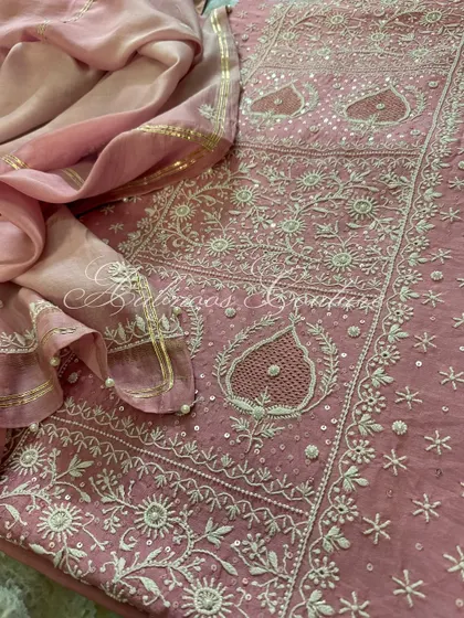 A detailed flat-lay of the blush pink suit, showcasing the intricate jaal work on the kurta and the coordinated, embellished dupatta.
