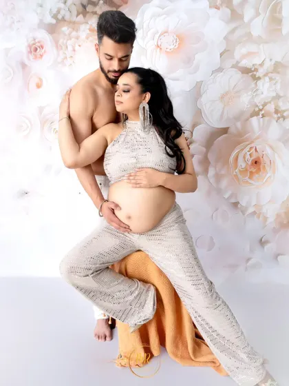 A stylish and confident pose from a modern maternity shoot. The couple's pose and the unique sequined outfit create a bold and fashionable statement.