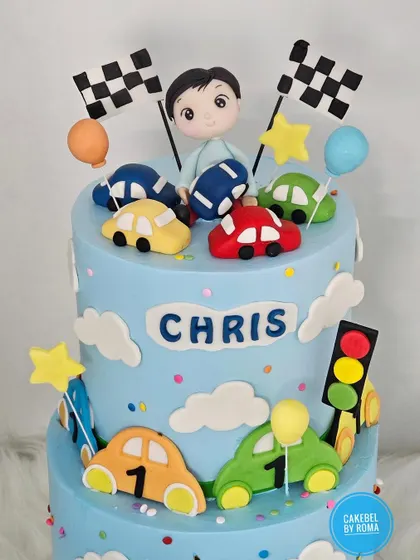 A detailed shot of the two-tier car cake, showing the custom figurine and colorful fondant cars.