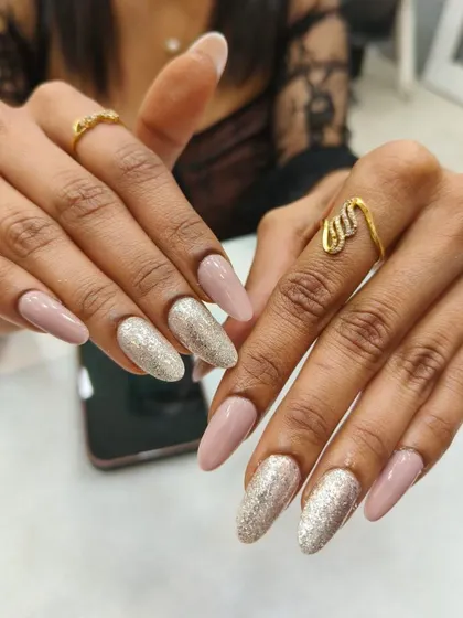 A chic and modern nail set featuring a neutral beige polish paired with a brilliant silver glitter accent nail. This combination is perfect for a sophisticated look with a touch of glamour.