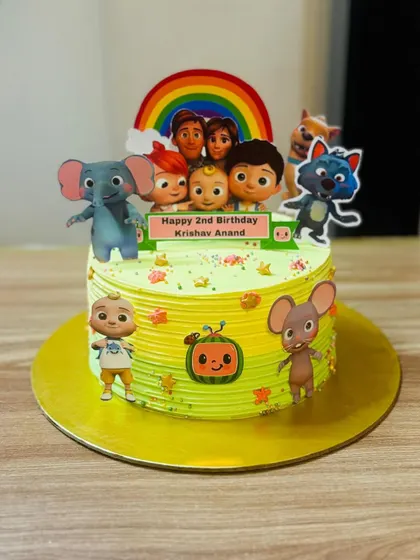 A bright and cheerful Cocomelon cake with a rainbow topper, perfect for a toddler's party.