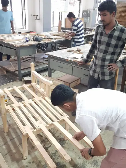 Students work together to assemble the frame of a solid wood chair, carefully fitting the joints and ensuring the structure is square and stable.