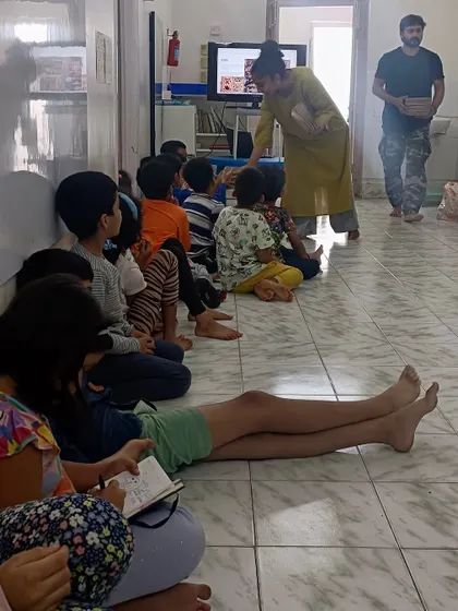 Children sit attentively as a parent volunteer shares stories and images of Karnataka's architecture, bringing history and culture to life in the classroom.