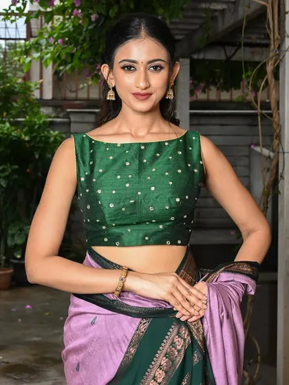 This sleeveless green boat-neck blouse is dotted with mirror work, adding a touch of sparkle to a simple and elegant design.