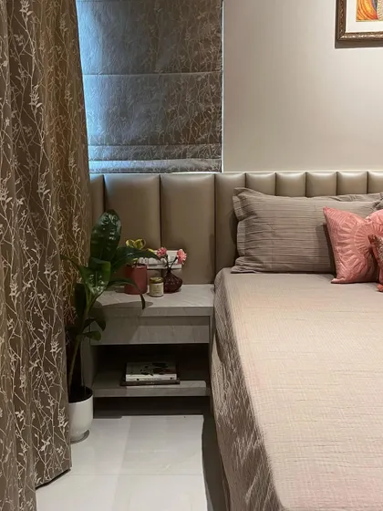 This bedroom design uses a neutral, earthy color palette to create a calming environment. The upholstered headboard extends across the wall, creating a seamless and sophisticated look.