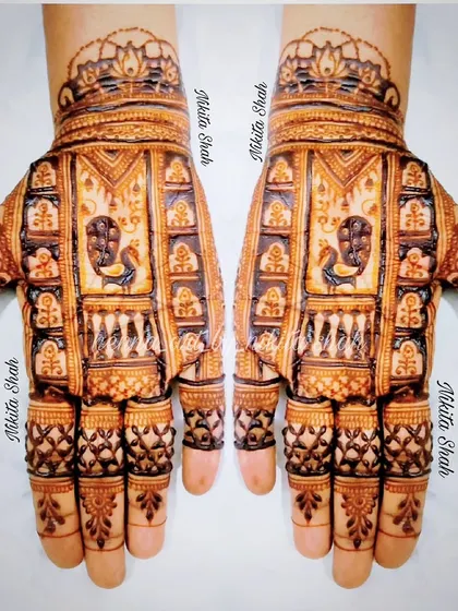 A detailed Indian mehendi design with a prominent peacock figure. The fine line work and checkerboard patterns showcase the intricacy of the art.