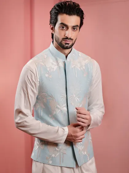 A close-up on the delicate white floral embroidery of the powder blue Nehru jacket. The tonal work adds texture and interest without overwhelming the serene color.