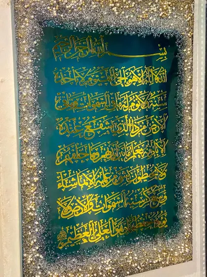A custom-made Ayat al-Kursi piece for a client, featuring a deep green background and a full, glittering border of crushed glass and crystals.