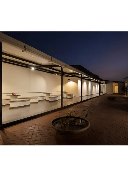 An evening view of the terrace at Land Capital Primero, showing an outdoor seating area. The lighting is designed to be soft and indirect, creating a relaxed ambiance.