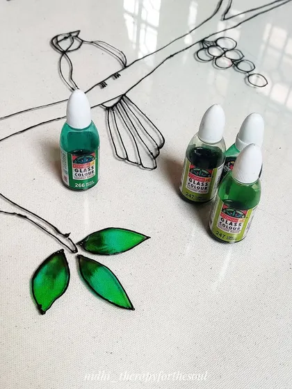 A work-in-progress detail shot, showing the first few leaves being filled with green glass paint. You can see the tools of the trade right next to the artwork.