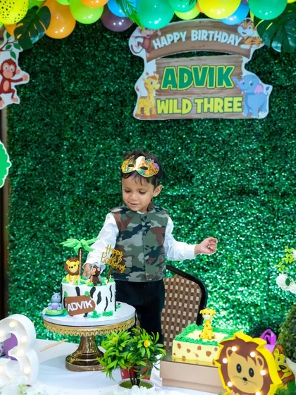 Ready to cut the cake. This little one is excited for his 'Wild Three' birthday celebration, complete with a jungle-themed cake.