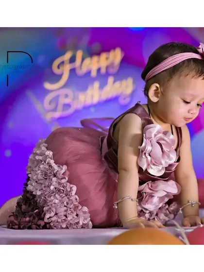 A cute shot of the little girl exploring her birthday setup, crawling among the balloons in her lovely party dress.