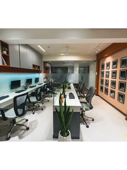 A view of our main workstation area, designed for collaboration and focus. The long desk is complemented by ergonomic chairs and a gallery wall of our proudest project moments.